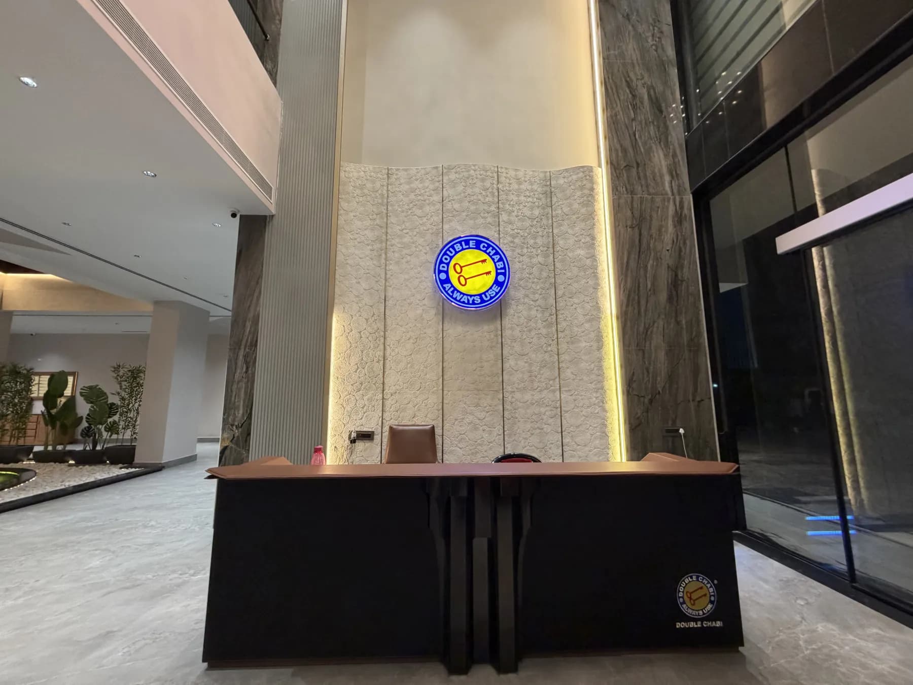The reception desk inside the main building, beneath the Double Chabi emblem on a stone wall.
